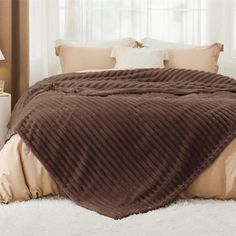 a bed covered in a brown blanket and pillows