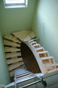 a staircase made out of wooden planks in the corner of a room with a skylight