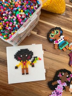 some beads are laying on a table next to a plastic container with scissors and other items