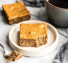 two pieces of cake on a plate next to a cup of coffee and a spoon