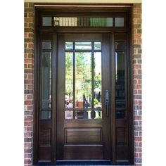 a wooden door with glass panels and sidelights on the outside of a brick building