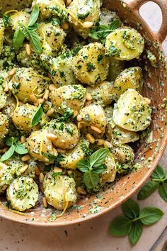 a bowl filled with pasta and pesto sprinkled on top of green leaves