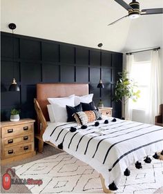 a bedroom with black and white bedding, wooden dressers and a ceiling fan