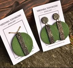 two green earrings with black and white designs on them are sitting next to each other