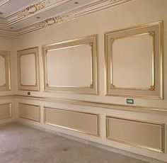 an empty room with gold framed mirrors on the wall