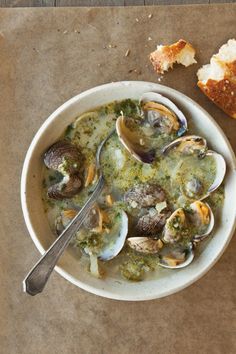 a bowl of soup with clams and bread on the side