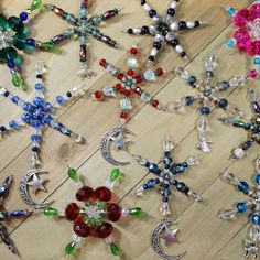 many different colored and shaped brooches on a wooden surface with beads hanging from them