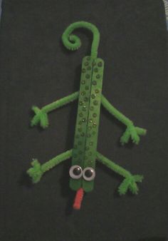 a green lizard made out of legos sitting on top of a black tablecloth