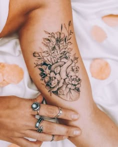 a woman's arm with flowers and an elephant tattoo on her left side ribcage