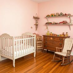 a baby's room with pink walls and wooden furniture