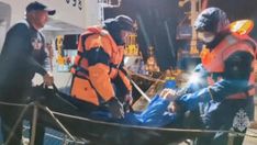 a group of people standing around a man in an orange life jacket on a boat