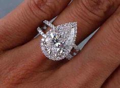 a woman's engagement ring with a pear shaped diamond in the center and pave band