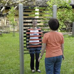 two people standing in front of a metal structure made out of strips of wood and wire