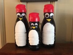 three penguin shaped salt and pepper shakers sitting on top of a wooden table in front of a door