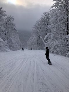 a person riding a snowboard down a snow covered road