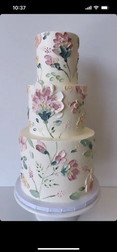 a three tiered white cake with pink flowers on it