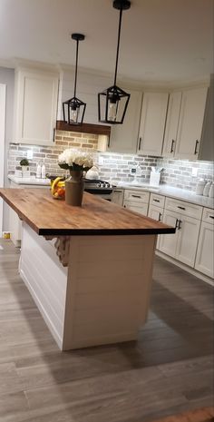 a kitchen with an island in the middle and lights hanging from the ceiling above it