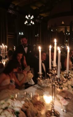 a group of people sitting around a table with candles