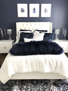 a white bed topped with pillows and blankets next to two framed pictures on the wall