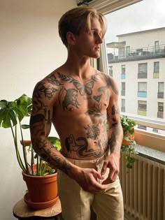 a man with tattoos standing in front of a window