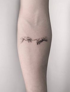 a woman's leg with a tattoo on it that has two hands touching each other