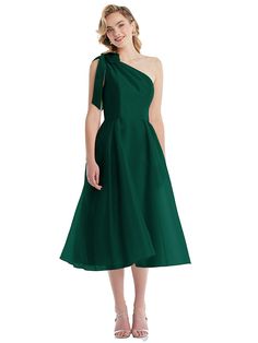 a woman wearing a green dress with one shoulder and an asymmetrical neckline