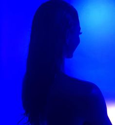 a woman with long hair standing in the dark