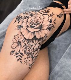 a woman's thigh with flowers and leaves on her leg, showing the tattoo design