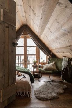 an attic bedroom with wooden walls and flooring is furnished with sheep rugs on the floor