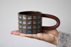 a hand holding a brown and blue mug