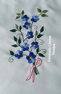 blue flowers with green leaves and red ribbon on white linens that have been embroidered onto