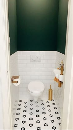 a white toilet sitting in a bathroom next to a green wall and black and white tiled floor