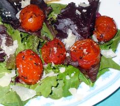 a salad with tomatoes, lettuce and parmesan cheese is on a plate