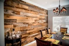 a dining room table with place settings on it and wooden wall in the back ground