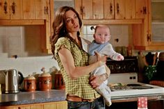 a woman holding a baby in the kitchen