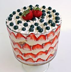 a trifle with strawberries and blueberries in it on a glass dish,