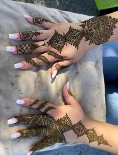 two hands with henna tattoos on them