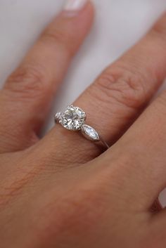 a woman's hand with a diamond ring on top of her finger and an engagement band