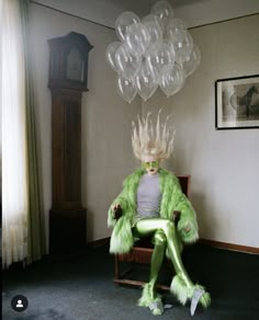 a woman sitting in a chair with balloons hanging from the ceiling above her head and legs