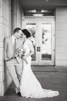 a bride and groom standing next to each other in front of a building on their wedding day