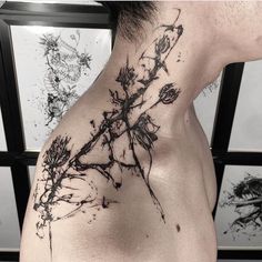 the back of a man's neck is covered with black ink and has flowers on it