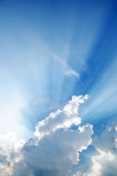 an airplane flying in the sky with sunbeams and clouds