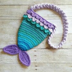 a crocheted bag with a mermaid tail on the side sitting on top of a wooden floor