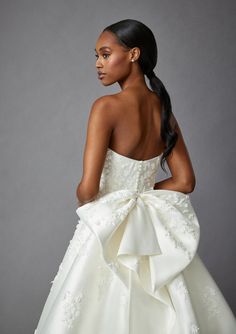 a woman in a white dress with a big bow on her back