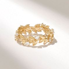 a gold ring with leaves and diamonds on it