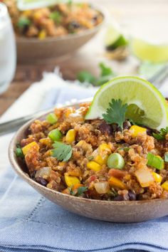 a bowl filled with mexican food and garnished with cilantro, lime wedges