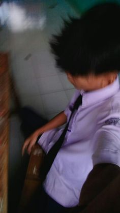 a young boy sitting on top of a wooden chair