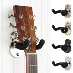 an acoustic guitar is mounted to the wall with three different styles of hooks on it