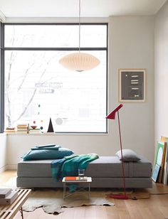 a living room filled with furniture and a large window next to a wall mounted poster