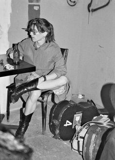 a woman sitting at a table with her legs crossed in front of her face, next to several suitcases